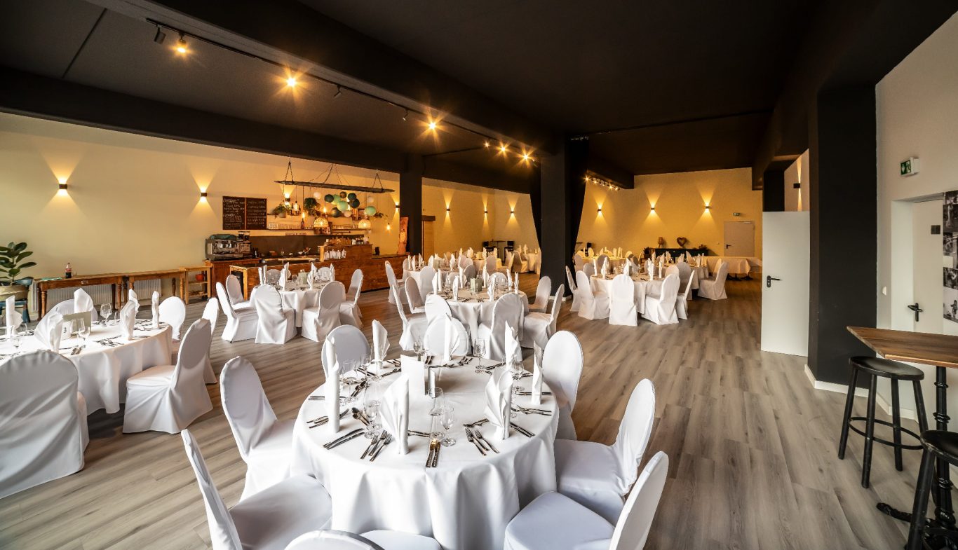 Eleganter Veranstaltungsraum mit runden Tischen und weißen Tischdecken.
