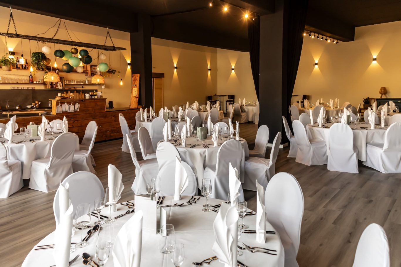 Elegant Restaurant mit runden Tischen, weißen Tischdecken und Stühlen für eine festliche Veranstaltung.
